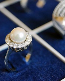 Close-up of a pearl ring with diamonds on a luxurious display.